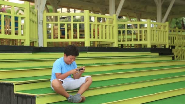 Bambino seduto su una scala con smartphone — Video Stock