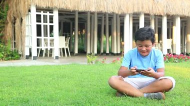 Genç çocuk oyun smartphone çimenlerin üzerinde