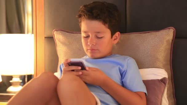Joven chico morena con teléfono inteligente en el dormitorio 2 — Vídeos de Stock