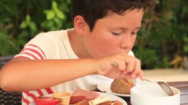 Kind eten van ontbijt in de tuin — Stockvideo