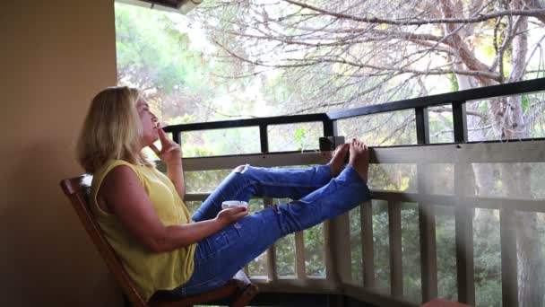 Balkon ve Sigara İçilmeyen üzerinde oturan kadın — Stok video