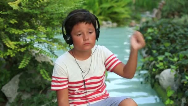 Criança com fone de ouvido relaxante no parque — Vídeo de Stock