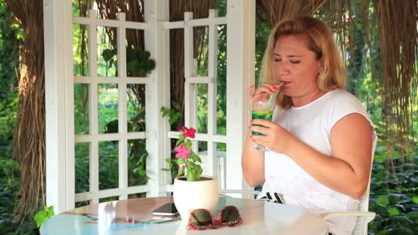 Mujer rubia con smartphone relajante en el café de verano — Vídeos de Stock