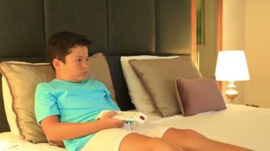 Bir yatakta yatarken ve yatak odasında 2 çizgi film izlerken çocuk