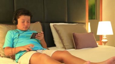 Çocuk bir yatakta yatarken ve Mp3 çalar ile müzik kulaklık ile