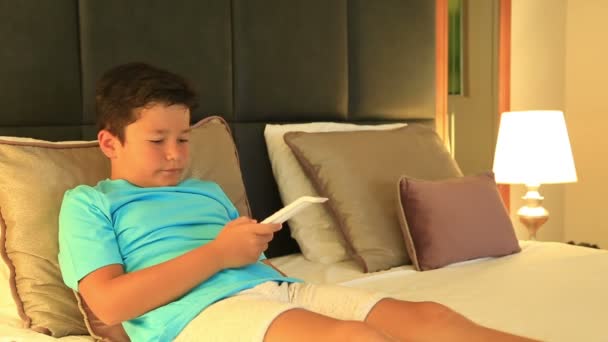 Enfant couché sur un lit et regardant un dessin animé dans la chambre — Video