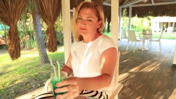 Kvinna sitter vid sommarcaféet och dricka cocktail — Stockvideo