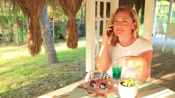 Donna seduta al caffè estivo a parlare al telefono — Video Stock