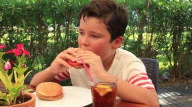Bir kafede hamburger yiyen çocuk