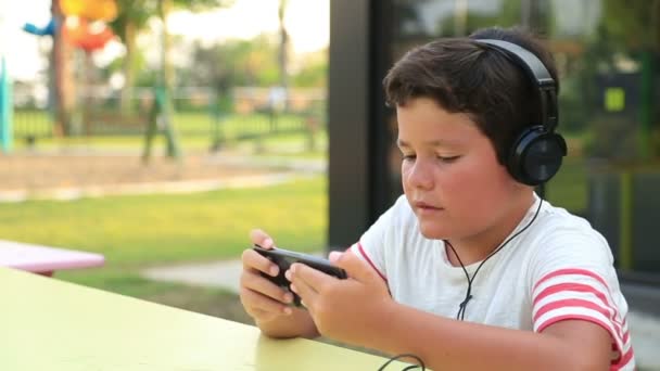 Ребенок слушает музыку и играет на смартфоне — стоковое видео