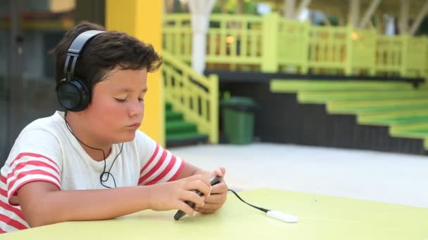 Niño en edad escolar usando smartphone al aire libre — Vídeo de stock