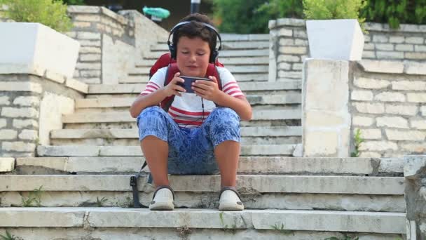 Barn med smartphone på utomhus — Stockvideo
