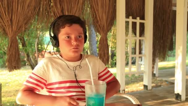 Niño con auriculares escuchando música en el café — Vídeos de Stock