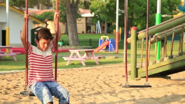 Bonito menino balançando no playground — Vídeo de Stock