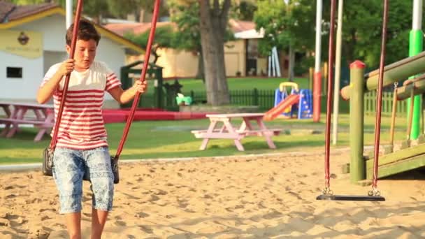 Netter kleiner Junge schaukelt auf dem Spielplatz — Stockvideo