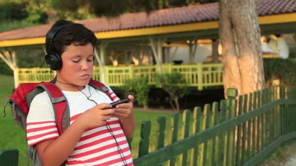 Happy little schoolboy listening to music and gaming on the smartphone — Stock Video