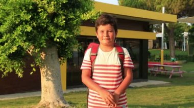 Bir kameraya gülümseyen sırt çantası ile bir öğrenci portresi