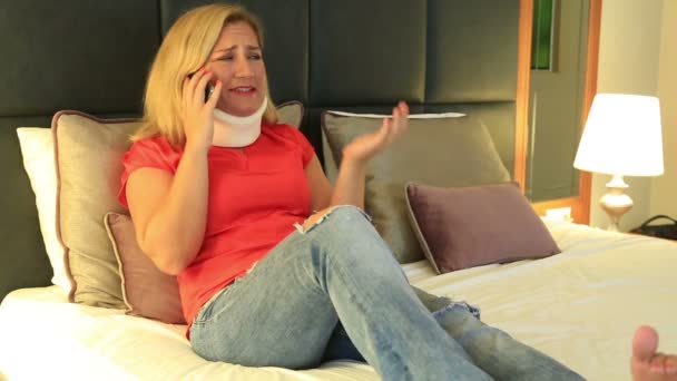 Painful woman with a neck brace talking on the phone — Stock Video