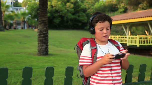 Skolpojke lyssnar på musik och spel på din smartphone — Stockvideo