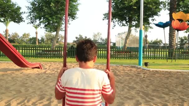 Несчастный ребенок, качающийся на детской площадке — стоковое видео