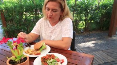 Hamburger ve salata restoranda yemek kadın