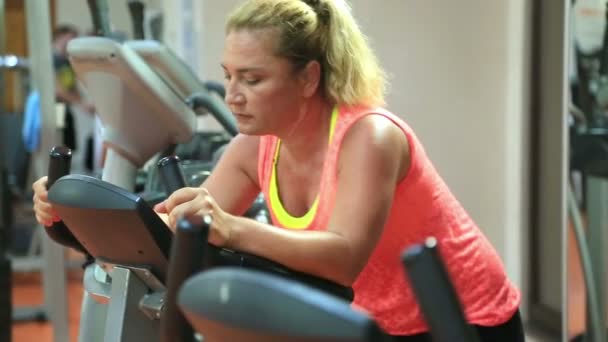 Mujer Entrenamiento en bicicleta de ejercicio en el gimnasio — Vídeos de Stock