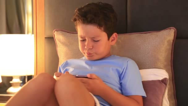 Young burunette child with smart phone in bedroom — Stock Video