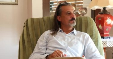Düşünceli, orta yaşlı bir adamın portresi. Evdeki kanepede oturuyor.