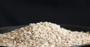 Siyah arkaplanda dönen pişmemiş yulaf yığını