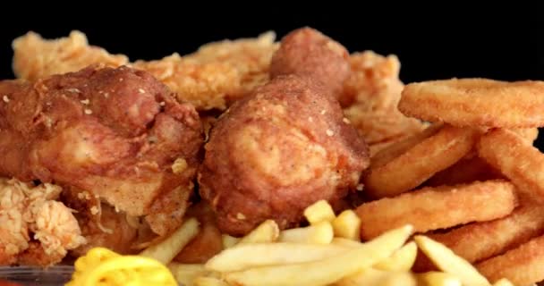 从宏观上看法式薯条和带有芥末和番茄酱的酥脆鸡块的黑色背景 — 图库视频影像
