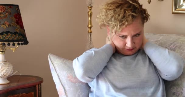 痛苦的女人坐在家里的沙发上按摩着脖子和肩膀 — 图库视频影像