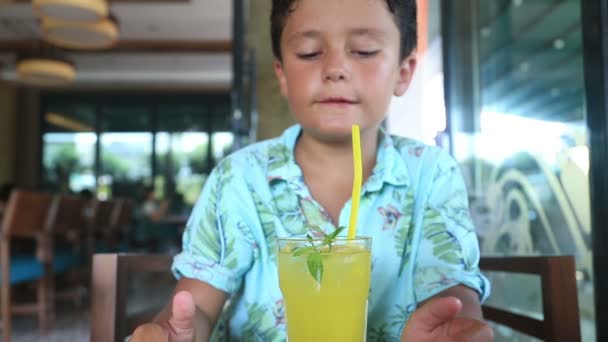 Niño en un café bebiendo limonato — Vídeo de stock
