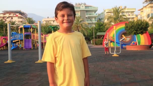 Enfant souriant et courant vers l'aire de jeux — Video