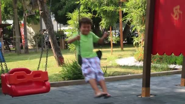 Boy on playground swing — Stock Video