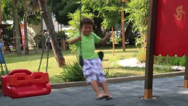 Menino no parque infantil balanço — Vídeo de Stock