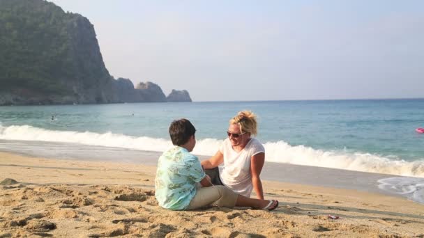 Mãe e filho sentados na praia e falando — Vídeo de Stock