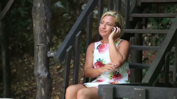 Kvinna sitter på park och talar i mobiltelefon — Stockvideo