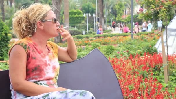 Sad woman smoking cigarette at the park — Stock Video