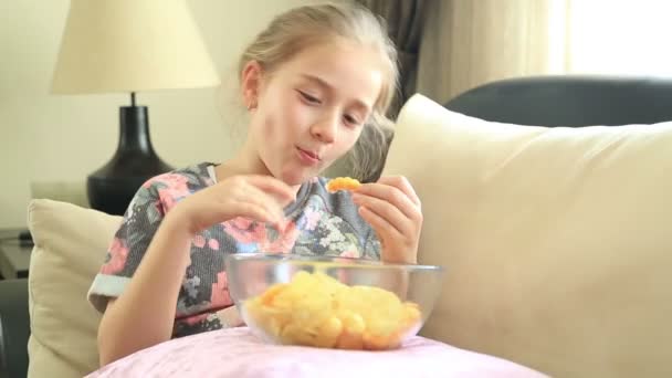 Счастливая маленькая девочка ест чипсы — стоковое видео