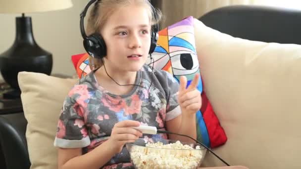 Bambina ascoltando musica e mangiando popcorn — Video Stock
