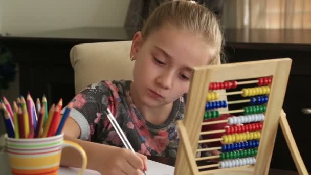 Маленька дівчинка вчиться вдома і їсть яблуко — стокове відео