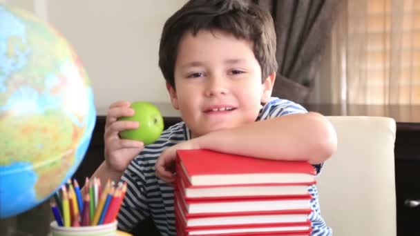 Junge im Grundschulalter posiert auf einem Stapel Bücher. — Stockvideo