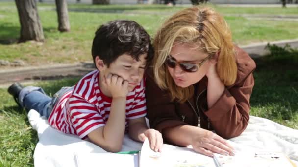 Μητέρα ανάγνωση στο γιο στο πάρκο — Αρχείο Βίντεο