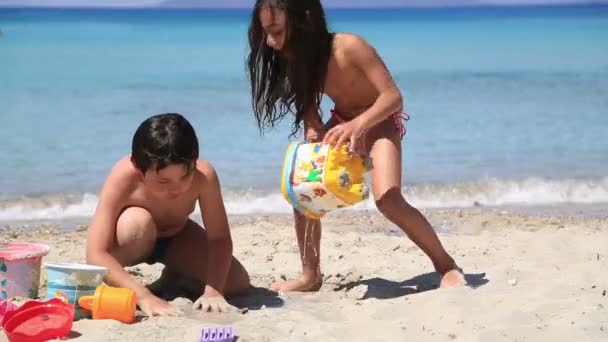 Malý chlapec a dívka si hraje na pláži — Stock video