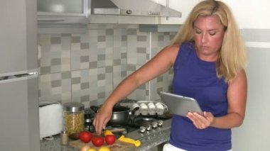 mutfakta yemek tablet bilgisayar kullanan kadın