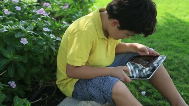 Молодий хлопчик грає на планшетному комп'ютері — стокове відео