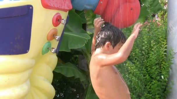 Child taking a cold shower in a waterpark and dancing — Stock Video