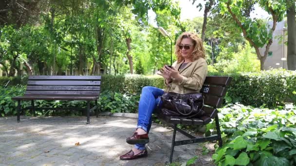 Жінка використовує смартфон у парку — стокове відео