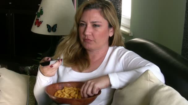 Женщина смотрит телевизор и ест чипсы — стоковое видео