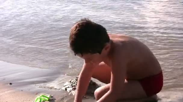 Niño jugando en la playa — Vídeo de stock